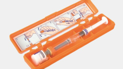 An orange plastic box containing an injector and small bottle. 