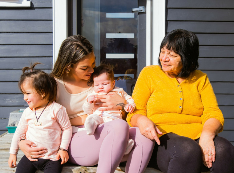 A family sit on the steps of a house